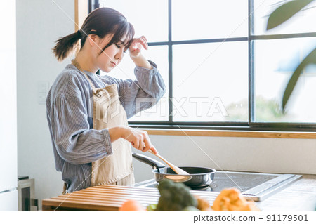 Female using a frying pan in the kitchen (tired) 91179501