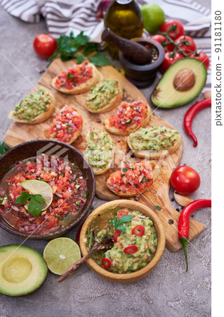 tasty salsa and guacamole bruschetta snacks at domestic kitchen on wooden cutting board tasty salsa and guacamole bruschetta snacks at domestic kitchen on wooden cutting board 91181180