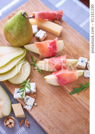 Jamon or prosciutto ham slices, Blue cheese, pears and walnuts on wooden board 91181190