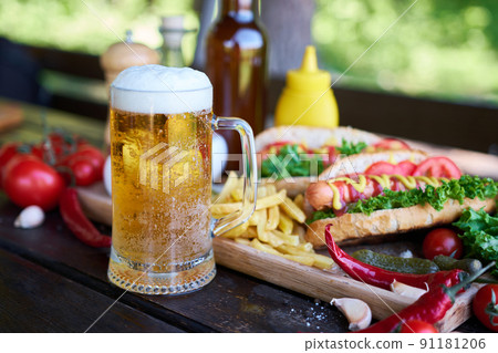 BBQ hot dog served with vegetables and French fries and sauces on wooden serving board BBQ hot dog served with vegetables and French fries and sauces on wooden serving board 91181206