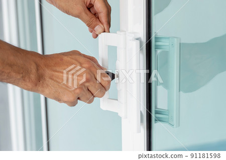 Man's hand opening a glass door with a key. Man's hand opening a glass door with a key. 91181598