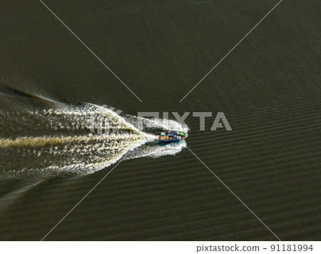 Motor boat floats on the dark water of the lake, aerial view. Background or texture 91181994