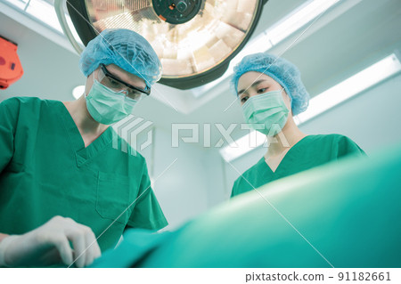 Low Angle Shot of Professional surgeons team performing surgery in operating room, surgeon, Assistants, and Nurses Performing Surgery on a Patient, health care cancer and disease treatment concept 91182661