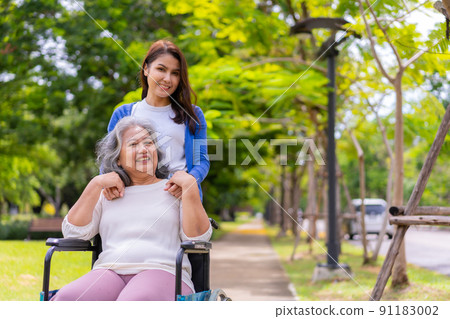 Asian careful caregiver or nurse taking care of the patient in a wheelchair. Concept of happy retirement with care from a caregiver and Savings and senior health insurance, a Happy family Asian careful caregiver or nurse taking care of the patient in a wheelchair. Concept of happy retirement with care from a caregiver and Savings and senior health insurance, a Happy family 91183002