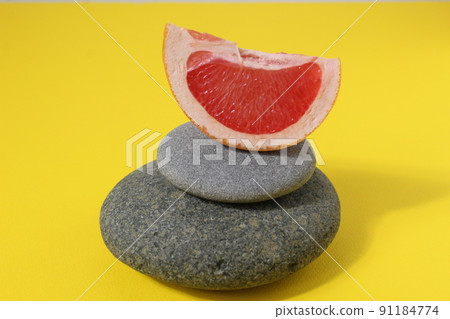 a ballans tower of grey stones and grapefruit orange fruit on a white yellow background with room for text. Benefits of Energy Health Importance Vitamin a ballans tower of grey stones and grapefruit orange fruit on a white yellow background with room for text. Benefits of Energy Health Importance Vitamin 91184774