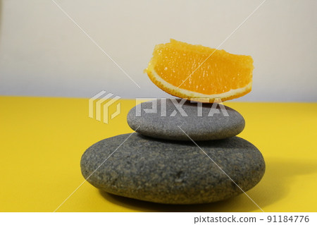 a ballans tower of grey stones and grapefruit orange fruit on a white yellow background with room for text. Benefits of Energy Health Importance Vitamin a ballans tower of grey stones and grapefruit orange fruit on a white yellow background with room for text. Benefits of Energy Health Importance Vitamin 91184776