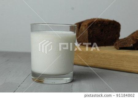 still life made from the milk of a cake cake on a board on a gray background. breakfast bread fruit milk. useful products 91184802