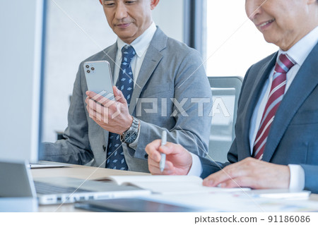 Up the hands of senior men who use smartphones in the office Up the hands of senior men who use smartphones in the office 91186086