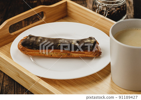 Eclair cake with chocolate glaze on wooden tray 91189427