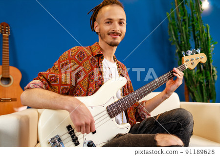 Young caucasian man with dreadlocks playing electric guitar in his room 91189628