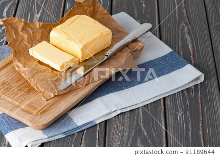 Wooden board with butter on blue checkered napkin 91189644