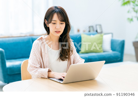 Young woman using a computer at home Young woman using a computer at home 91190346