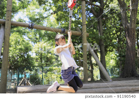 Elementary school girl playing with Tarzan rope (7 years old) 91190540