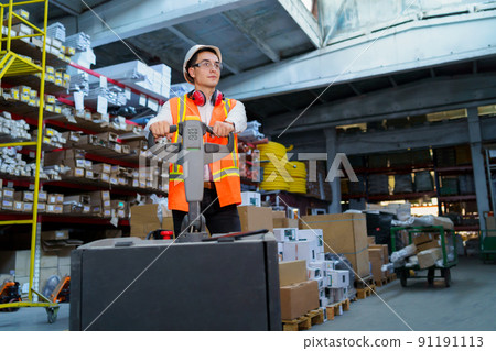 Warehouse worker operates a pallet loader Warehouse worker operates a pallet loader 91191113