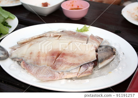 Fresh Gray pomfret, Chinese silver pomfret fish cut into pieces arranged in a white plate topped with ice. On the wooden table in the restaurant, prepare for the shabu pot. Selective focus. Fresh Gray pomfret, Chinese silver pomfret fish cut into pieces arranged in a white plate topped with ice. On the wooden table in the restaurant, prepare for the shabu pot. Selective focus. 91191257