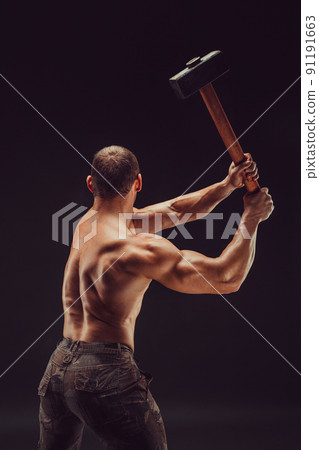 Back view of a muscular man with great anatomy posing on a black background with a big hummer in his hands 91191663