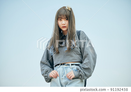 Gen Z woman standing against the blue sky 91192438