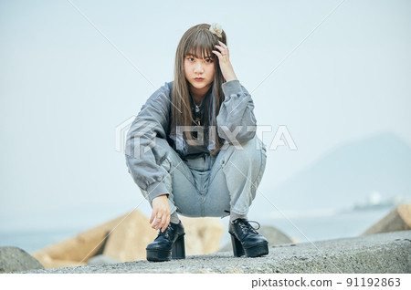 Gen Z woman sitting looking at the camera against the blue sky 91192863