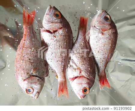 Cooking fresh fish on foil. Top view and close up. Healthy sea food. Diet meal preparation. Cooking fresh fish on foil. Top view and close up. Healthy sea food. Diet meal preparation. 91193902