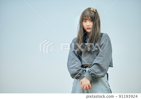 Gen Z woman standing against the blue sky 91193924