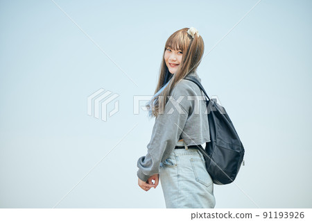 Gen Z woman standing against the blue sky 91193926