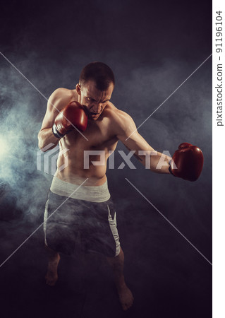Muscular kickbox or muay thai fighter punching in smoke 91196104