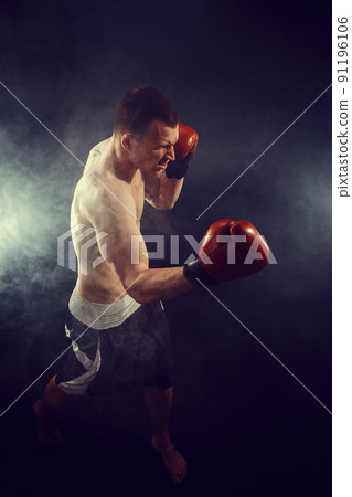 Muscular kickbox or muay thai fighter punching in smoke Muscular kickbox or muay thai fighter punching in smoke 91196106