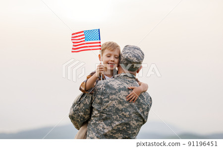 Happy boy son with american flag hugging father came back from US army Happy boy son with american flag hugging father came back from US army 91196451