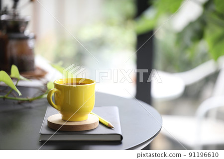 Yellow coffee cup and notebook and plant pot  91196610