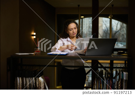 Charming woman interior designer drawing sketch, creating new home design project, working on laptop in a cozy interior design studio 91197213