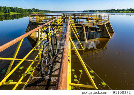 Bicycle on the yellow spilway of river dam 91198372
