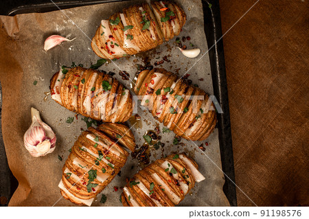 Hasselback Baked Potatoes with Fresh Herbs and pork fat, lard, tallow, garlic. National Ukrainian food. Top view. 91198576