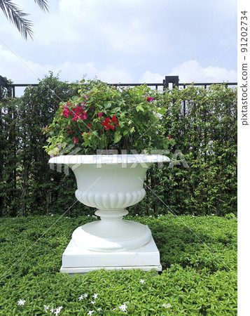 Roman flower style ornamental pot in the garden Roman flower style ornamental pot in the garden 91202734