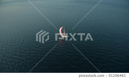 Aerial shot of a moving sailing yacht with pink sail on the sea 91206461