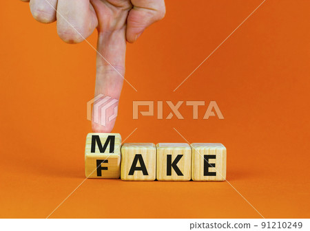 Fake it until you make it symbol. Businessman turns a wooden cube and changes the word Fake to Make. Beautiful orange background. Business, and fake it till you make it concept. Copy space. 91210249