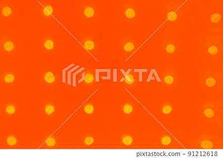 Orange abstract paper background with small round holes arranged in a row and glowing against the light background 91212618