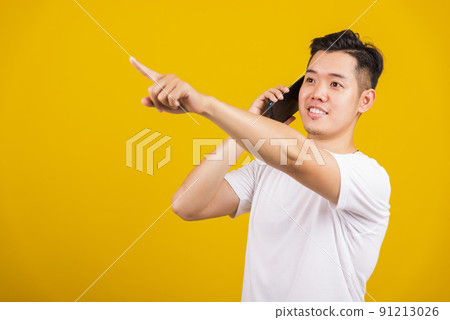 young man smiling positive showing smartphone blank screen and pointing finger to side away 91213026
