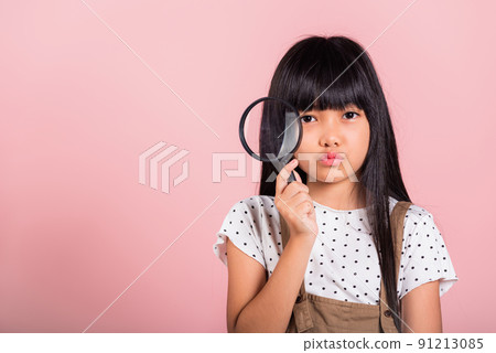 Asian little kid 10 years old funny looking through magnifying glass 91213085