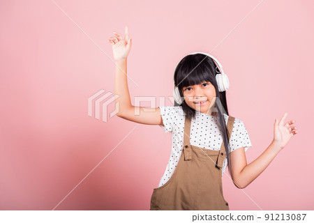 Asian little kid 10 years old smiling listening music wearing wireless headset and dancing 91213087