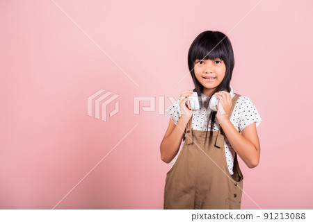 Asian little kid 10 years old smiling listening music wearing wireless headset around neck 91213088