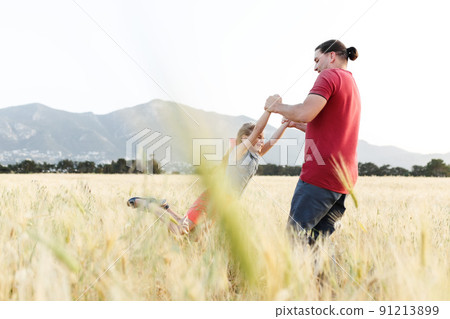 Dad spins his daughter on field , having fun at sunset. Father plays with child. Happy family and childhood concept. Dad spins his daughter on field , having fun at sunset. Father plays with child. Happy family and childhood concept. 91213899