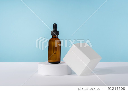 Oil cosmetics amber product packaging with stylish props. Serum cosmetic bottle with peptides and retinol on platform pedestal on blue background. Serum dropper Oil cosmetics amber product packaging with stylish props. Serum cosmetic bottle with peptides and retinol on platform pedestal on blue background. Serum dropper 91215308