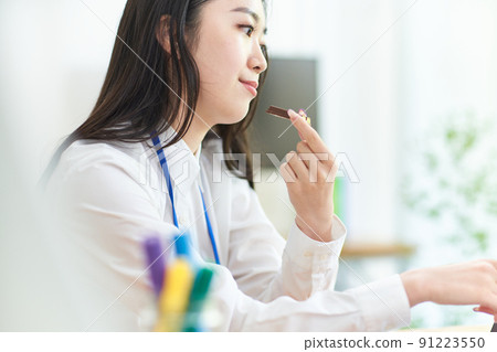 一個二十多歲的女人，一邊工作一邊吃巧克力 91223550