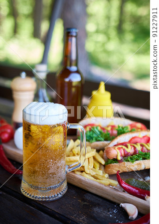 BBQ hot dog served with vegetables and French fries and sauces on wooden serving board 91227911