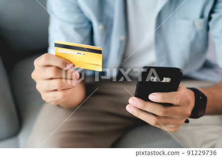Man holding credit card and using smartphone for online shopping, internet banking, e-commerce, spending money, working from home concept 91229736