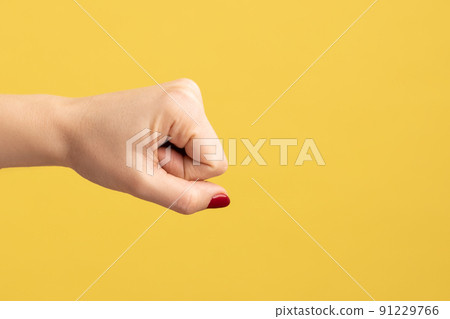 Profile side view closeup of woman hand showing boxing fists with hand, attack or defense against problems. Indoor studio shot isolated on yellow background. 91229766