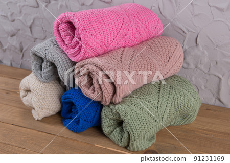 six colored sweaters twisted into rolls and laid out on the table in a pyramid 91231169