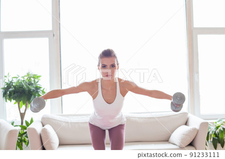 Active woman doing fitness exercises with dumbbells at home. Sport and recreation concept. 91233111