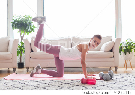 Donkey kicks exercise. Fit woman doing fitness donkey kicks exercise indoor at home Donkey kicks exercise. Fit woman doing fitness donkey kicks exercise indoor at home 91233113