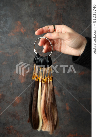 Female hand holds hair samples on dark background 91233740